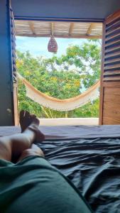 a person laying on a bed looking out a window at Chalé Green Vila Mathilde in Icapuí +6 photos