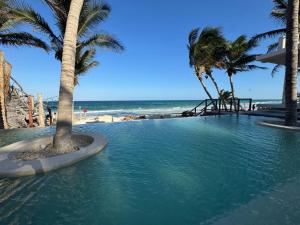 a swimming pool next to a beach with palm trees at Azucar Hotel Tulum in Tulum