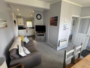 a living room with a couch and a clock on the wall at Overlooking the Norfolk Broads in Carlton Colville