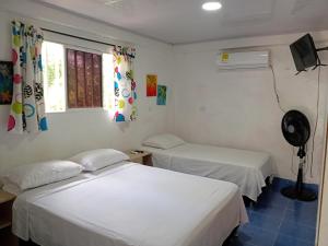 Dos camas en una habitación con paredes y ventanas blancas. en Casa turistica Miss G, en Providencia