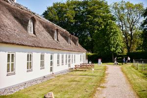 a building with a thatched roof and a table and benches at Sankt Helene Tisvildeleje in Tisvildeleje