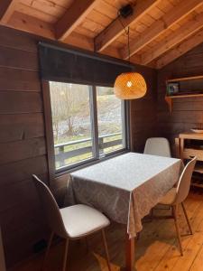 a table and chairs in a room with a window at Barlindbotn feriehytte med båtutleige in Kvalsvik