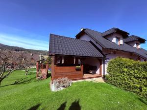 a house with a deck on a green lawn at Apartmány u tenisového kurtu in Mosty u Jablunkova