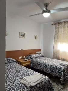 a hotel room with two beds and a ceiling fan at Hostal Restaurante el Cazador in Nuévalos