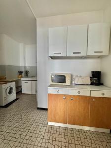 a kitchen with white cabinets and a microwave at Aqua Appartement in La Grande-Motte