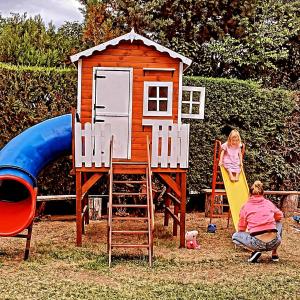 two children playing on a playground with a house at Cantonavi Cabañas in Mina Clavero