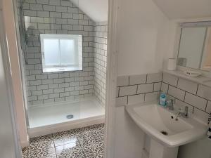 a white bathroom with a sink and a shower at 1 bed-cottage-Parking-Patio-close to coasts in North Hill +29 photos