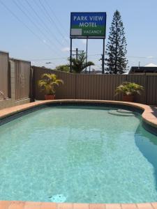a green and white swimming pool with a blue sign at Park View Motel in Gladstone