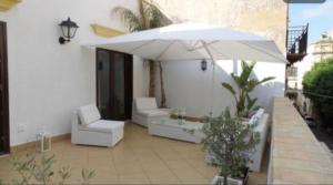 a patio with a white umbrella and two chairs and a table at La Terrazza in Marsala
