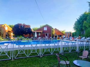 a swimming pool with tables and chairs in front of a house at Cantonavi Cabañas in Mina Clavero +78 photos