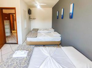 a room with three beds in a room at Avenida Plaza Hotel in Pindamonhangaba
