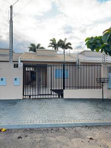 a gate in front of a building with palm trees at Casa elegante, próximo às cataratas in Foz do Iguaçu
