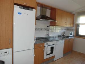 a kitchen with a white refrigerator and a stove at Zona Las Catedrales Barreiros Playa de Altar in Villadaíde