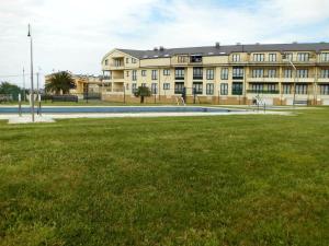 a large building with a grass field in front of it at Zona Las Catedrales Barreiros Playa de Altar in Villadaíde