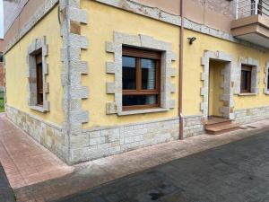 a yellow building with windows on a street at La Casuca de Corrales in Los Corrales de Buelna