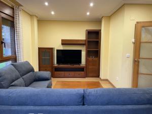 a living room with a blue couch and a tv at La Casuca de Corrales in Los Corrales de Buelna