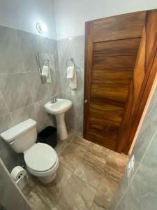 a bathroom with a toilet and a sink and a wooden door at Hotel Rincón Madera in Zihuatanejo +30 photos
