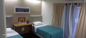 a room with two beds and a desk with a mirror at Victoria 3 Bed and Breakfast in Ezeiza