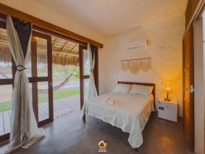 a bedroom with a bed and a large window at Moitas chalés in Amontada