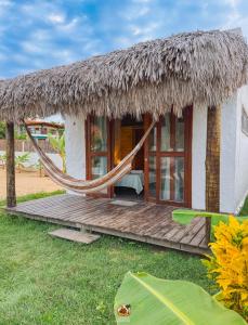 a thatch roof hut with a hammock in front of it at Moitas chalés in Amontada