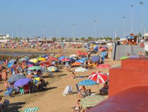 a crowd of people sitting on a beach with umbrellas at La Marea in Chipiona