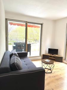 a living room with a couch and a large window at Petite Calédonie-Clim-Proche mer in La Grande-Motte