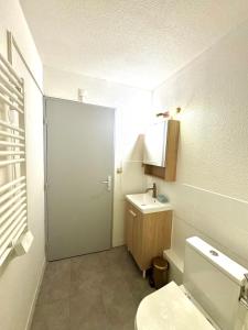 a bathroom with a toilet and a sink and a door at Petite Calédonie-Clim-Proche mer in La Grande-Motte