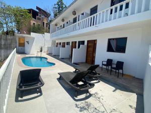 a patio with chairs and a swimming pool next to a building at Hotel Rincón Madera in Zihuatanejo