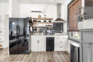 a kitchen with white cabinets and a black refrigerator at Old Spanish House Suite B Downtown Retreat in Biloxi