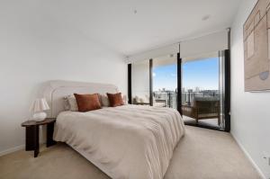 a white bedroom with a large bed and a balcony at Seren - Luxury Ocean Views With Pool And Gym in Gold Coast +34 photos