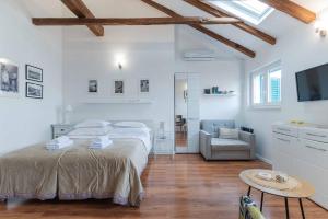 a white bedroom with a large bed and a chair at Apartment The Charm in Split