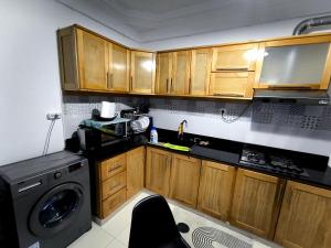 a kitchen with wooden cabinets and a washing machine at Appartement cosy à Reghaia Plage pour les familles in Reghaïa +3 photos