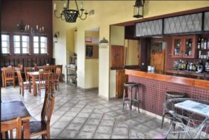 a restaurant with a bar with wooden tables and chairs at Posada los Carabeos in Arroyal