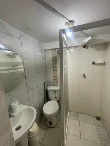 a white bathroom with a toilet and a sink at CÓMODA HABITACIÓN CENTRAL in Machala