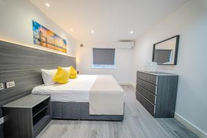 a bedroom with a large bed with yellow pillows at Ilford Luxury Apartments in Ilford