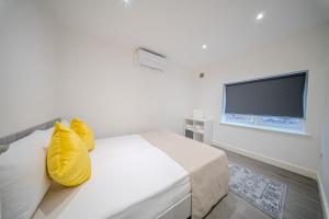 1 dormitorio con 1 cama con almohadas amarillas y TV de pantalla plana en Ilford Luxury Apartments, en Ilford 27 fotos más