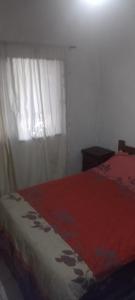a bedroom with a bed with a red blanket and a window at Arroyo seco playa hermosa in Arroyo Seco