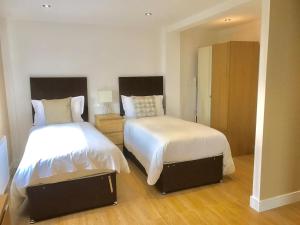 a bedroom with two beds with white sheets at Ilford Tower Apartments in Ilford +20 photos