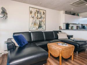a living room with a black leather couch and a table at 4 person holiday home in Lemvig in Lemvig