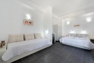 two beds in a bedroom with white walls and tile floors at Pancratium Villas & Suites in Akrotiri