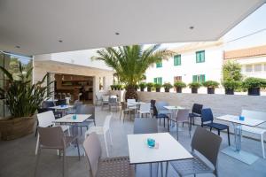 a restaurant with white tables and chairs at Avis Hotel in Novalja