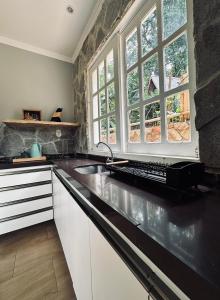 a kitchen with a sink and two windows at Villa Suíça Guaramiranga in Guaramiranga