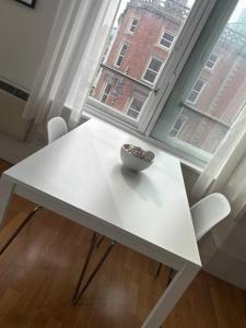 a white table with a bowl on it next to a window at Cozy Studio Apartment in Leeds +2 photos