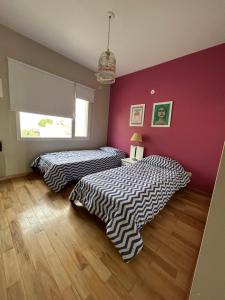 twee bedden in een kamer met roze en paarse muren bij Refugio Sur in Puerto Madryn