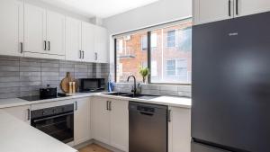 a kitchen with white cabinets and a stainless steel refrigerator at Bangalee 2 at Sunrise in Soldiers Point