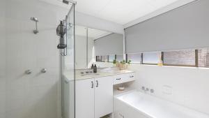 a white bathroom with a tub and a sink and a mirror at Bangalee 2 at Sunrise in Soldiers Point