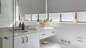 a white bathroom with a sink and a mirror at Bangalee 2 at Sunrise in Soldiers Point +18 photos