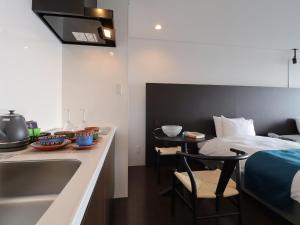 a kitchen with a counter and a sink and a bed at 真常寺読谷サロン in Yomitan