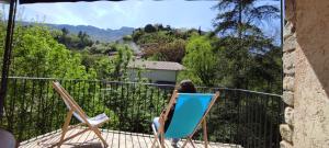 una donna seduta su una sedia su un balcone di Maison en Drôme provençale a Eygaliers