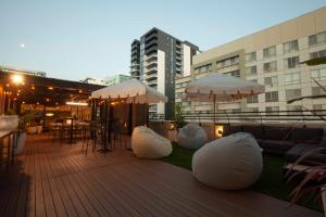 a deck with white bean bags and tables and umbrellas at Little Drifter Canberra in Canberra